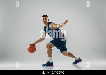 Young basketball player of team wearing sportwear training, practicing in action, motion in run isolated on white background. Concept of sport, movement, energy and dynamic, healthy lifestyle. Stock Photo
