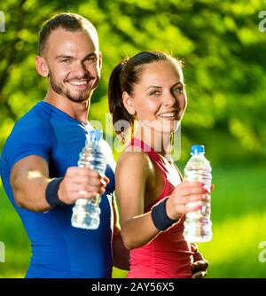 Man and woman drinking water from bottle after fitness sport exercise Stock Photo