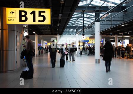 Airport terminal gate with gate number for departing flights, passengers waiting with luggage and suitcase Stock Photo