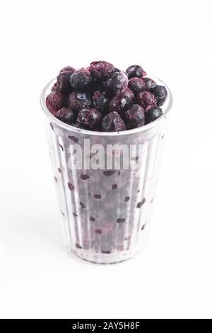 Glass full of frozen blueberries, frost glass, white background Stock Photo