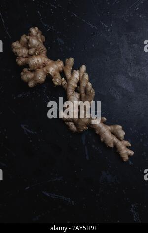 Big fresh ginger root on a black distressed background, Flat lay, dark food Stock Photo