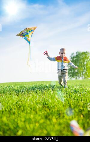 Young boy playing with his kite in a green field. Stock Photo