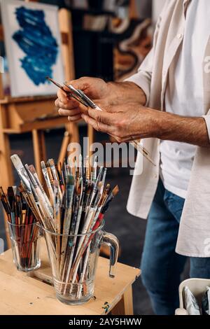Cropped shot of artist choosing brushes in workshop Stock Photo