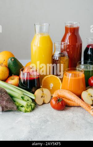 Healthy vegetable and fruit juices or smoothie in glass bottles, ripe slices of orange, apple, red tomato, carrot, celery, avocado isolated on white b Stock Photo