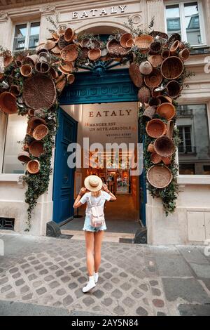 26 July 2019, Paris, France: Happy woman traveler standing at the entrance to unusual shop with baskets Stock Photo