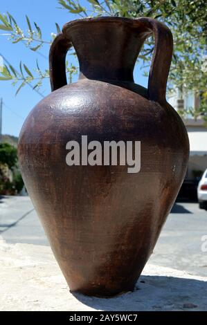 An amphora of brown color on a wall in stones. Stock Photo