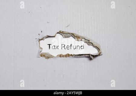 The word tax refund appearing behind torn paper. Stock Photo