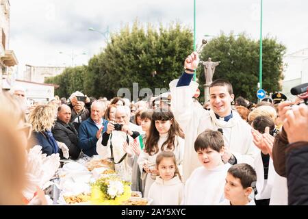 AVETRANA, ITALY - MARCH, 19, 2019. The priest blesses the food. Italian Easter tradition from Salento: Tria di St. Giuseppe, the distribution of food Stock Photo