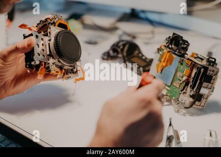Maintenance support and repairing service. Unrecognizable repair man uses special tools, repairs disassembled device in workshop. Close up shot. Hobby Stock Photo