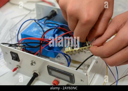 Skilled worker works on a power supply unit and connects wires Stock Photo