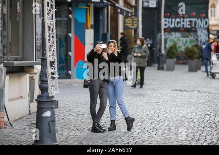 Bucharest, Romania - February 12, 2020: Two young women take a selfie on the streets of Old Town Bucharest. Stock Photo