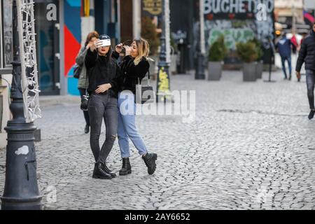 Bucharest, Romania - February 12, 2020: Two young women take a selfie on the streets of Old Town Bucharest. Stock Photo