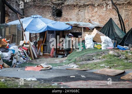 Bucharest, Romania - February 12, 2020: Extremely poor people living in a makeshift shelter in between garbage and a ruined building. Stock Photo