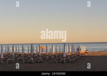 closed umbrellas and sun beds on the sandy beach in Italy Stock Photo