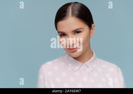 Headshot of pleasant looking dark haired female has pleased facial expression, dressed elegantly, has black combed hair, poses for making photo, isola Stock Photo
