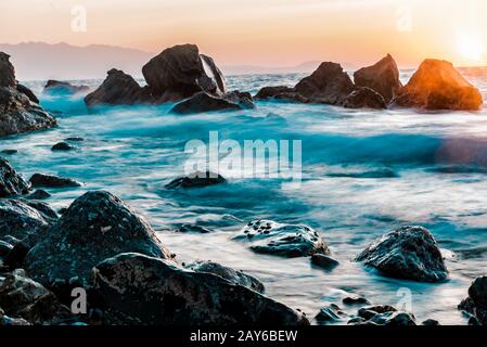 Beautiful sunset with crashing waves, long exposure shot, Greece Stock Photo