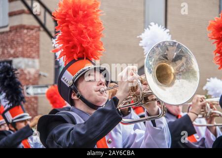8-28-2019 Tahlequah USA - Young man in uniform enthusiastically plays the trombone in a high school marching band parade with other band members blurr Stock Photo