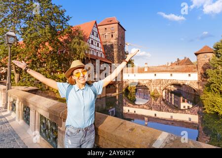 Happy asian woman tourist enjoying sunset view of the old town of Nurnberg city and Pegnitz river. Travel and student lifestyle in Germany Stock Photo