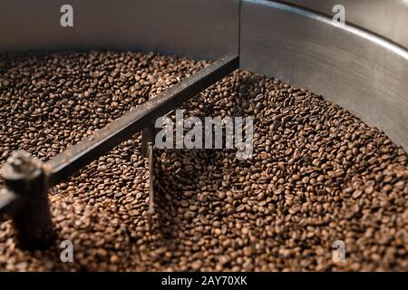 Freshly roasted coffee beans get sifted and stirred in  roasting machine Stock Photo