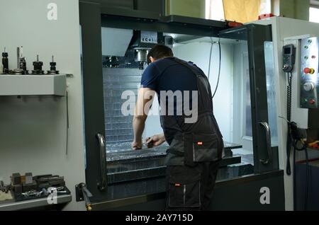 Worker fixing metal piece on the worktable of the milling machine Stock Photo