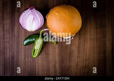Craft beef burger with cream cheese, purple onion, jalapeno pepper on wood table and rustic background Stock Photo