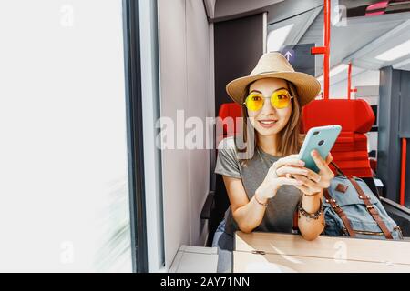 Asian happy woman using smartphone inside far distant train. Railroad Travelling and internet connection concept Stock Photo