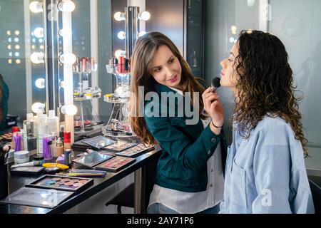 Professional make up artist doing makeup to a beautiful young girl into the cute study Stock Photo