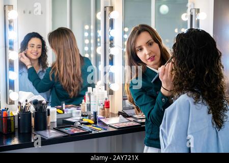Professional make up artist doing makeup to a beautiful young girl into the cute study Stock Photo