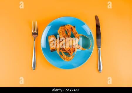 Top view of orange measuring tape on the blue plate. Diet concept. Stock Photo
