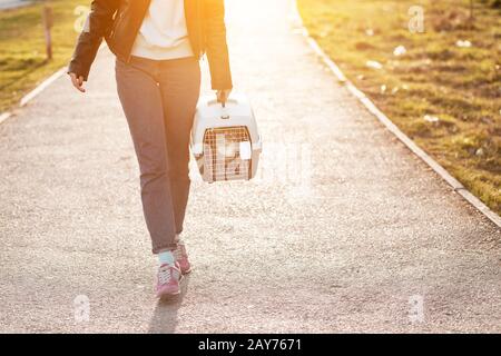 Girl pet owner carries her cat in a special plastic cage carrier for a walk or in a veterinary clinic Stock Photo