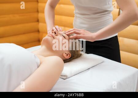 Close-up of therapist doing face massage at spa Stock Photo