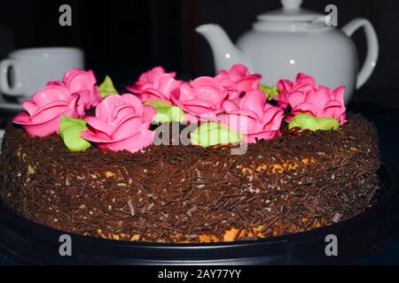 Delicious birthday cake on table close-up. Celebratory cake and tea set on a table on a dark background close-up. Stock Photo