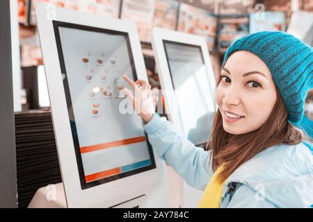 A woman orders food in the touch screen terminal with electronic menu in fast food restaurant Stock Photo