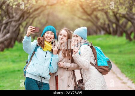 Three young pretty girls making selfie photo in spring park, sisterhood concept Stock Photo