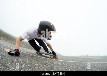 A young guy in a full face helmet in a slide passes a turn Stock Photo