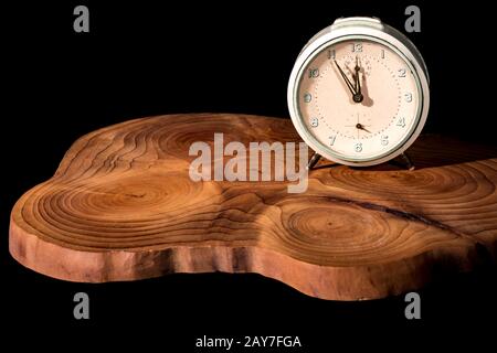 Old alarm clock five to twelve on a wooden board Stock Photo