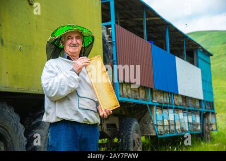 A beekeeper man holds a frame with honeycomb-filled honeycombs Stock Photo