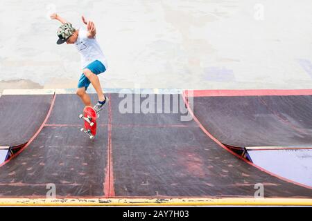 Teen skater hang up over a ramp on a skateboard in a skate park Stock Photo