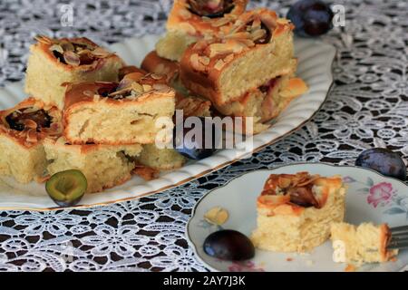 Cake with plums and almond flakes. Homemade cake. Cake with fruit. A delicious and light dessert. Plum cake. Sponge Cake with fruits. Stock Photo