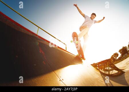 Teen skater hang up over a ramp on a skateboard in a skate park Stock Photo
