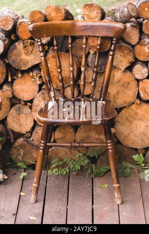 old vintage chair against the background of a log of wood sawnwood Stock Photo