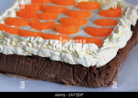 Chocolate cheesecake with mandarins. A delicate chocolate cheesecake. A delicate cake. Homemade cake. Cheesecake with whipped cream and fruit. Stock Photo