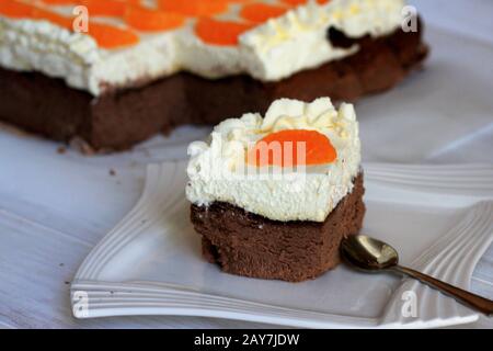 Chocolate cheesecake with mandarins. A delicate chocolate cheesecake. A delicate cake. Homemade cake. Cheesecake with whipped cream and fruit. Stock Photo