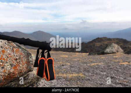 Professional sticks for climbing a mountain near a stone on a high mountain path against a blue sky and white clouds. Stock Photo