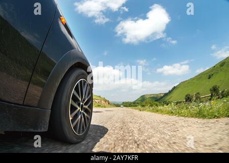 A close-up of the side of the car and a spinning wheel that rides along the asphalt at high speed Stock Photo