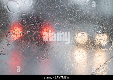 heavy rain on car windscreen and out of focus car lights - UK Stock Photo