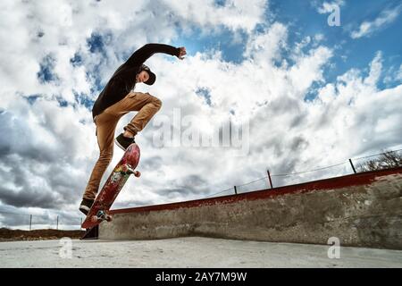 A young skateboarder makes Wallie in a skatepark, jumping on a skateboard into the air with a coup Stock Photo