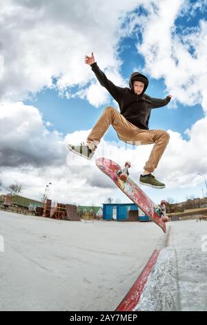 A young skateboarder makes Wallie in a skatepark, jumping on a skateboard into the air with a coup Stock Photo