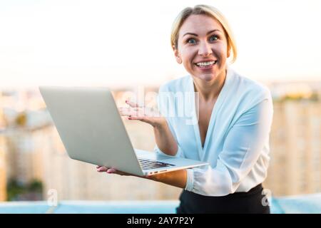 Beautiful smart business lady stand on the roof with laptop in h Stock Photo
