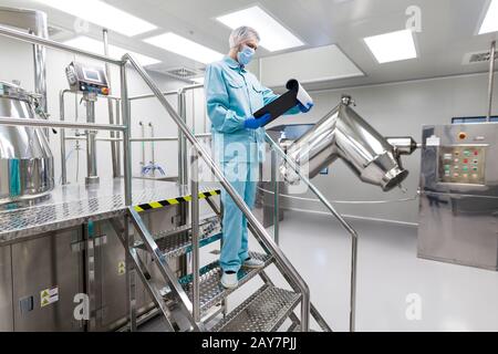 plant picture, scientist is standing on ladder in laboratory, checking readings Stock Photo